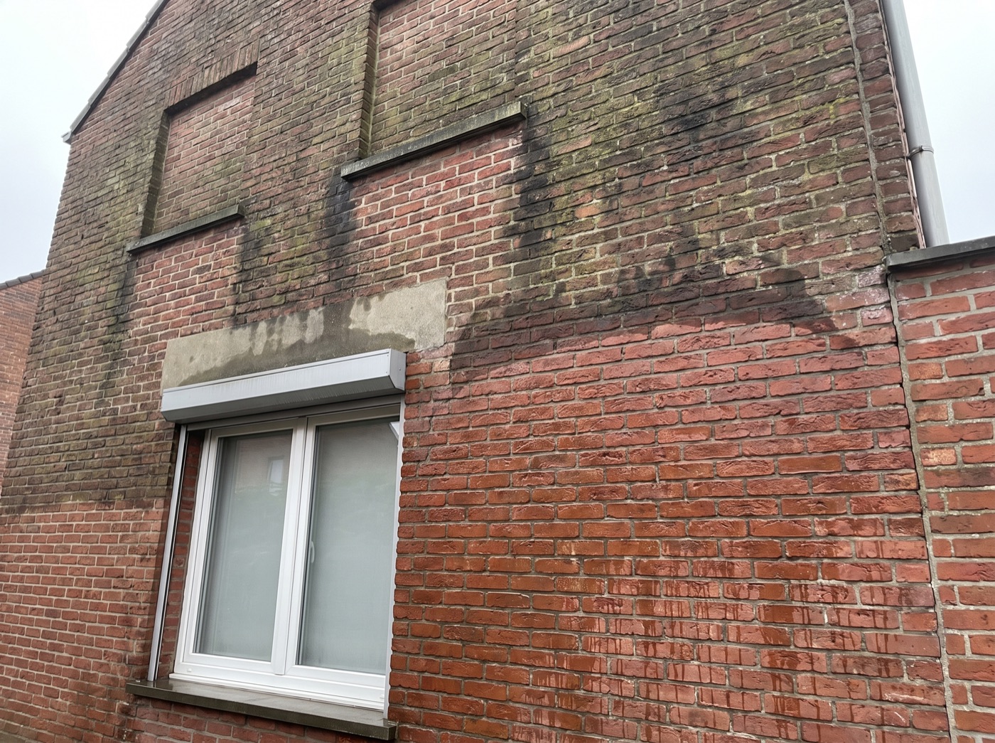 Bakstenen gevel: bovenaan nog groen en zwart, onderaan weer proper rood